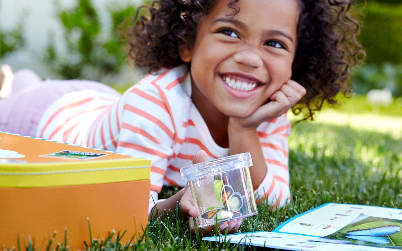 Child doing a Little Passports activity on the grass
