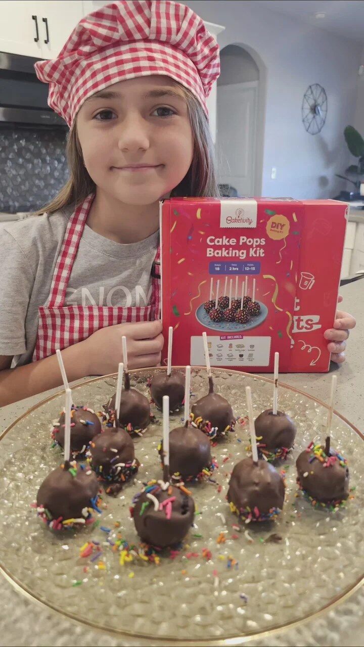 Girl in a chef hat showing homemade cake pops and the Baketivity box