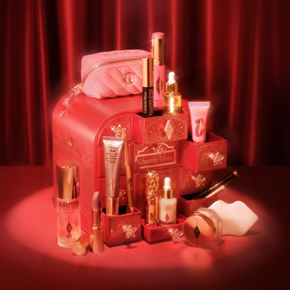 The Charlotte Tilbury Hollywood Beauty Wonderland Advent Calendar 2026, a red and gold box with open drawers holding Pillow Talk lipstick, Magic Cream and other products
