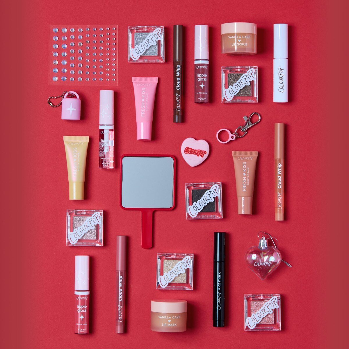 All 25 items from the ColourPop Colour Me Merry advent calendar laid out on red