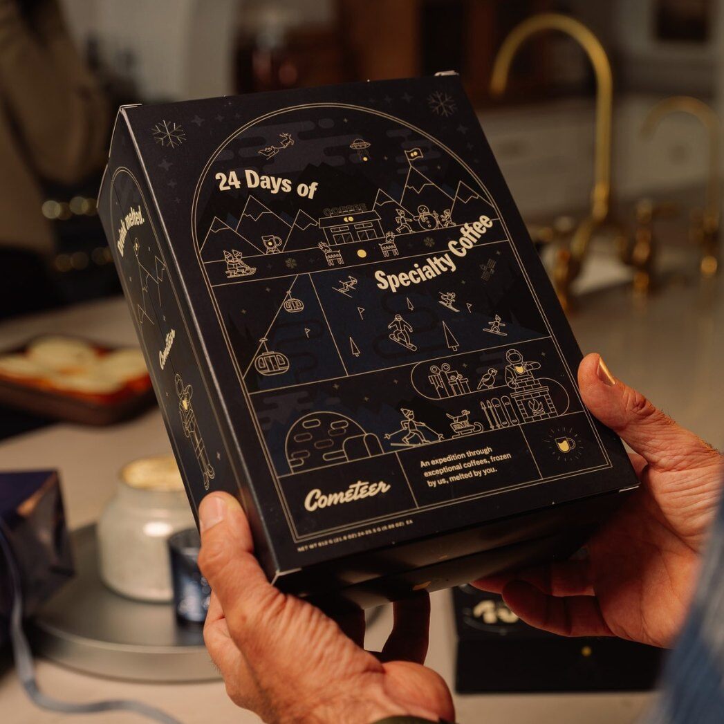 Hands holding the black Cometeer 24 Days of Specialty Coffee Advent Calendar 2026 box