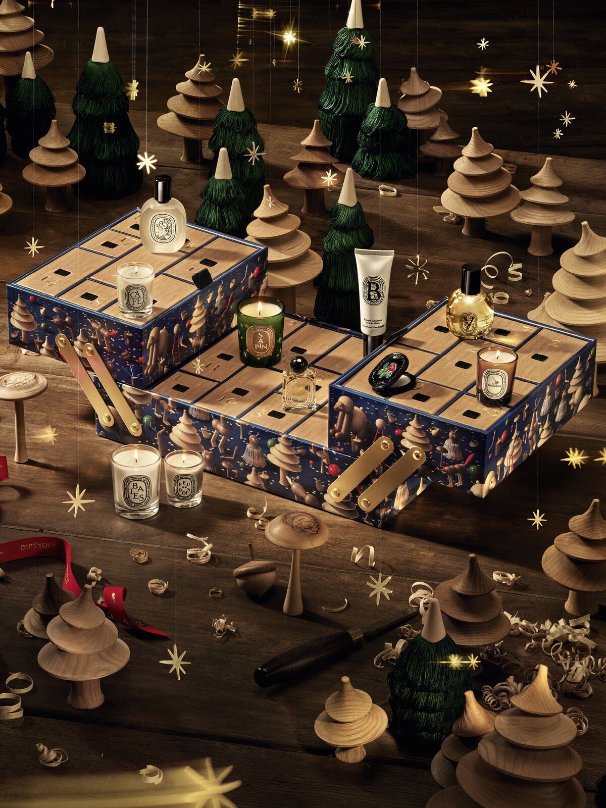 The Diptyque Advent Calendar 2026 opened like a toolbox with its candles and perfumes on top, among wooden fir trees and gold stars