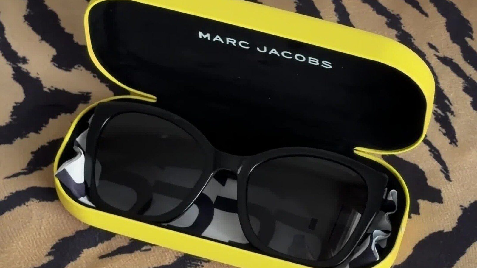 Black Marc Jacobs J Marc sunglasses in a yellow case on a tiger print throw, a FabFitFun Winter 2026 Luxe Choice
