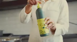 Cook squeezing a Graza olive oil bottle in a home kitchen