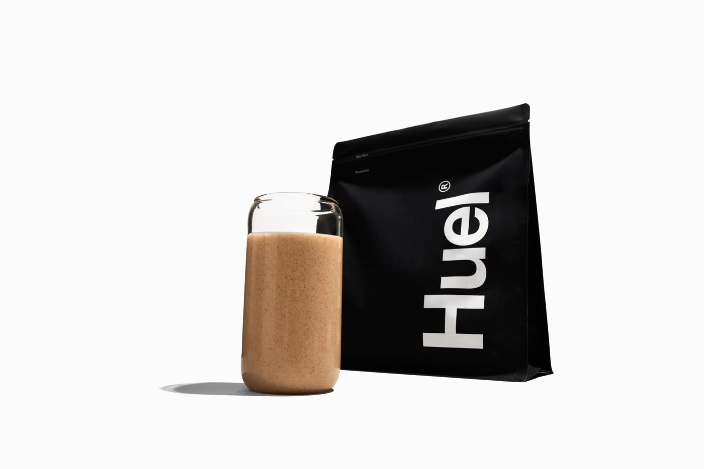 Huel Black Edition pouch next to a glass of chocolate shake