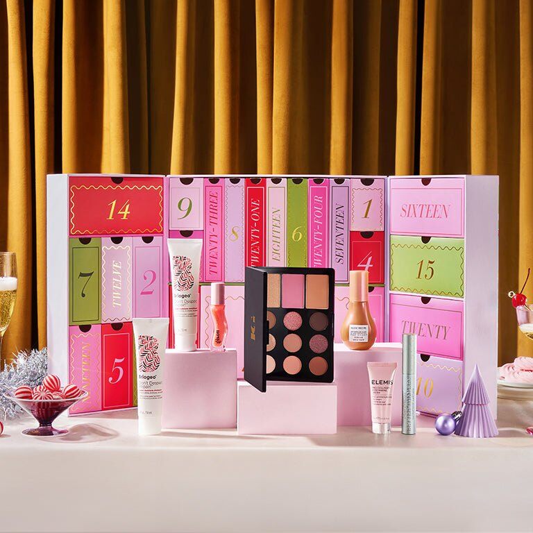 The IPSY Advent Calendar 2026 in pink, red and green Beauty Land packaging, with Briogeo, ELEMIS, Laura Geller and Maison Louis Marie products in front