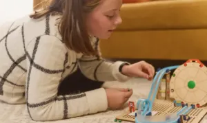 Child building a KiwiCo hands-on project on the living room floor