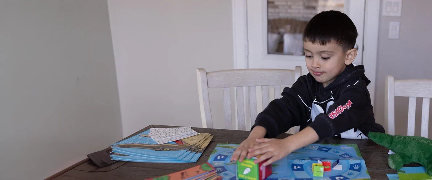 Boy playing an animal learning game from My ZOO Box at the kitchen table