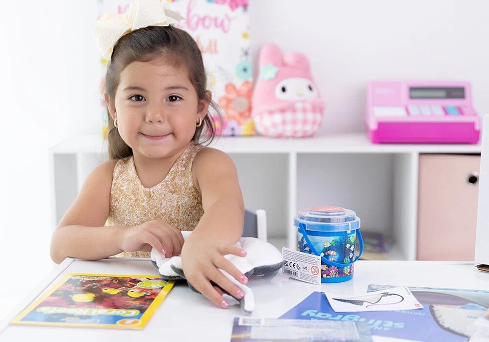 Smiling girl with her My ZOO Box plush and activity sheets