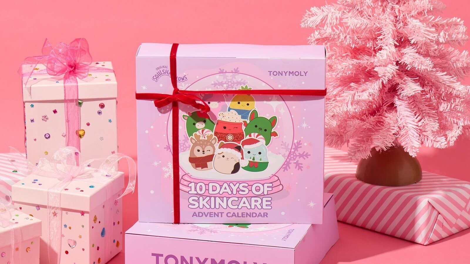 Squishmallows x TONYMOLY 10 Days of Skincare Advent Calendar tied with a red ribbon next to a pink Christmas tree and gifts