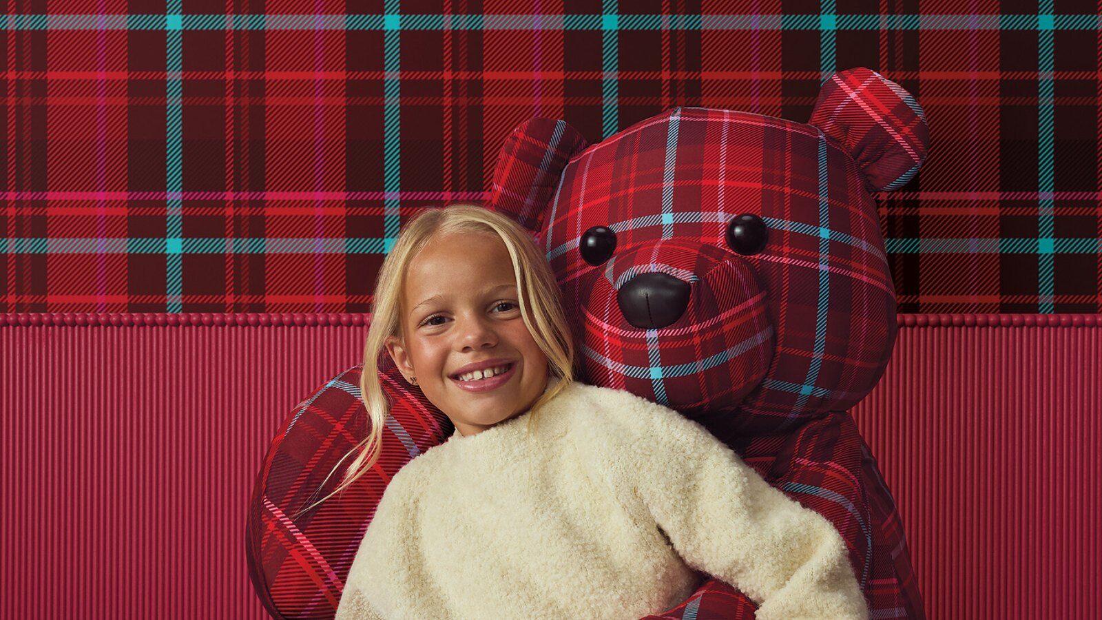Girl hugging a plaid teddy bear gift from Target's 2026 holiday collection