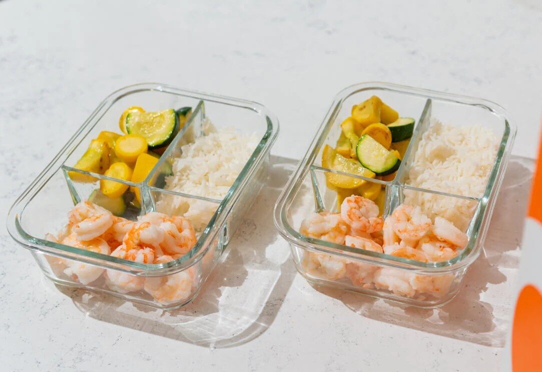 Two glass containers of Trifecta Meal Prep shrimp, rice and vegetables