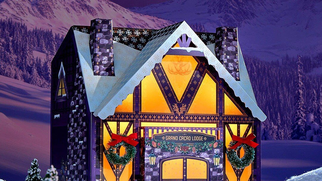Vosges 2026 advent calendar shaped like a lit ski lodge in the snow