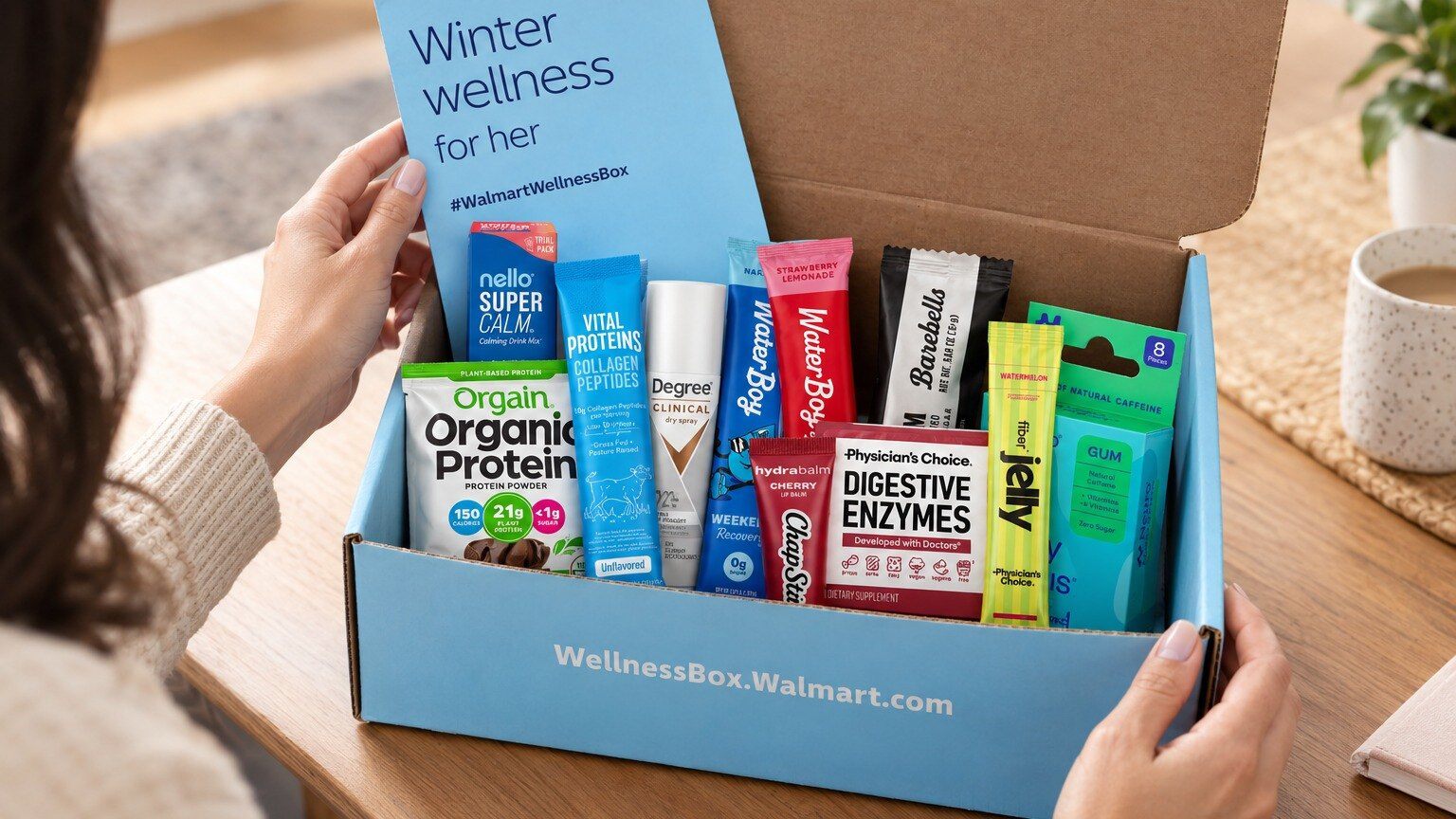 Hands opening the Walmart Wellness Box Winter for her, filled with Orgain protein, Vital Proteins, Waterboy and Barebells